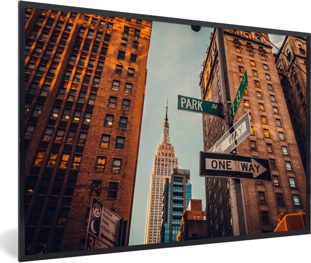 MuchoWow Gerahmtes Poster Das Empire State Building zwischen den hohen Gebäuden in New York 90x60 cm - Poster mit Schwarzem Bilderrahmen Wandpos...