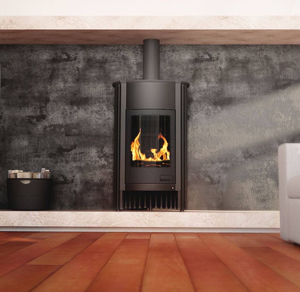 A modern living room with a black wood-burning stove as the focal point, set against a textured gray wall and a light-colored shelf. The floor is made of warm-toned wooden planks.