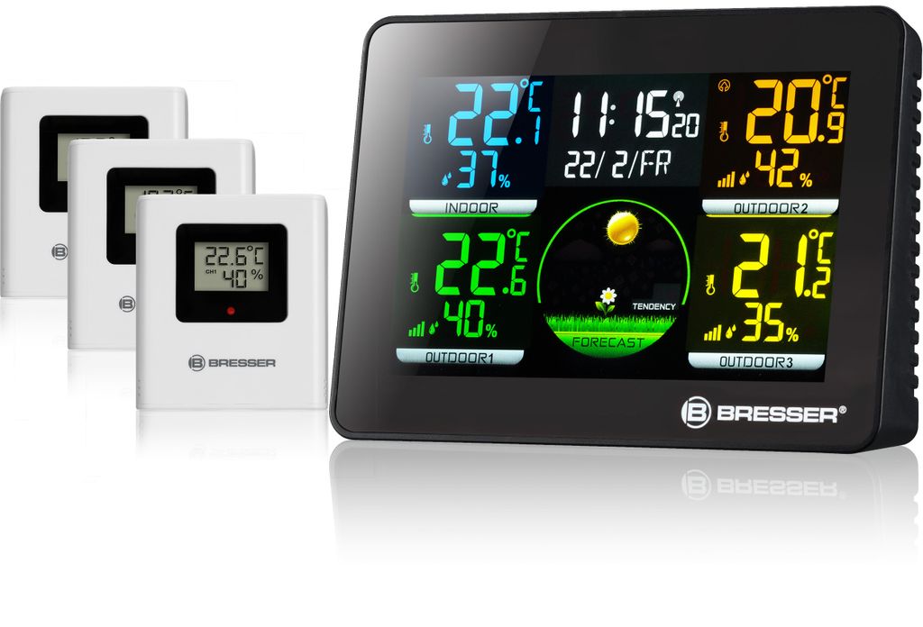 A black digital weather station with multiple outdoor sensors displayed on a white surface.