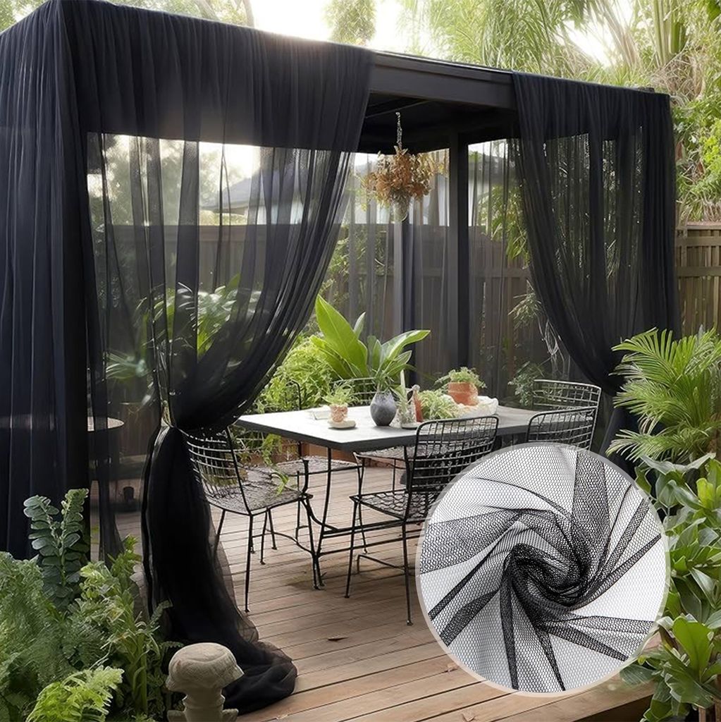 Outdoor patio area with a table and chairs covered by black sheer curtains.