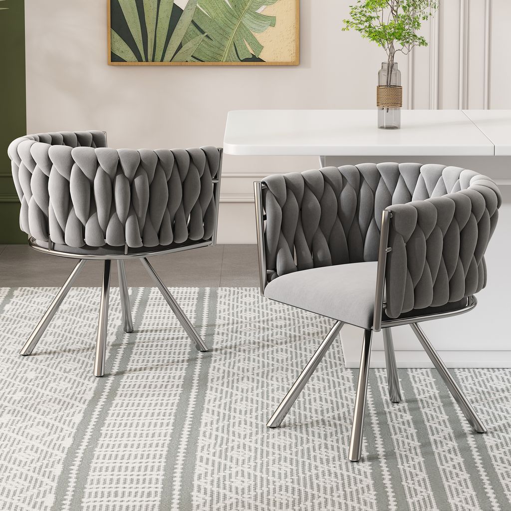 Two gray upholstered dining chairs with silver metal legs are shown in a dining room setting.