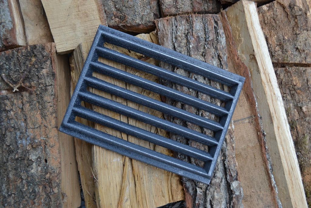 A cast iron grate is placed on a pile of chopped wood.