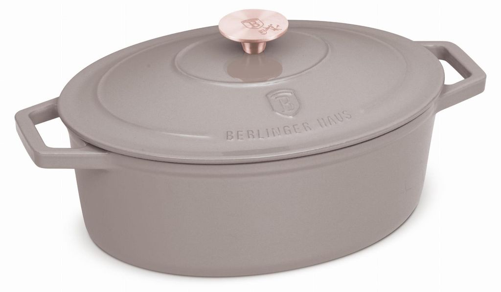 A taupe oval cast iron Dutch oven with a rose gold knob on the lid, shown from a diagonal angle against a white background.