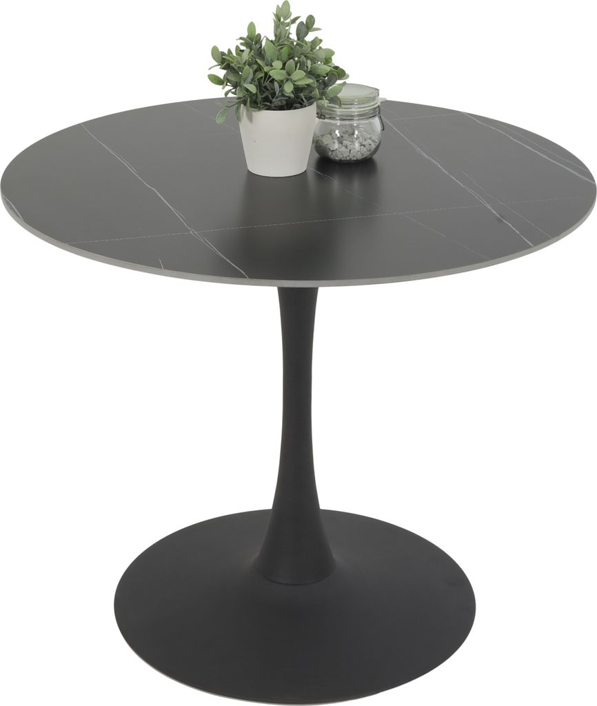 A round black marble-look dining table with an anthracite trumpet base, shown from a side angle with a small potted plant and a jar of pebbles on top.