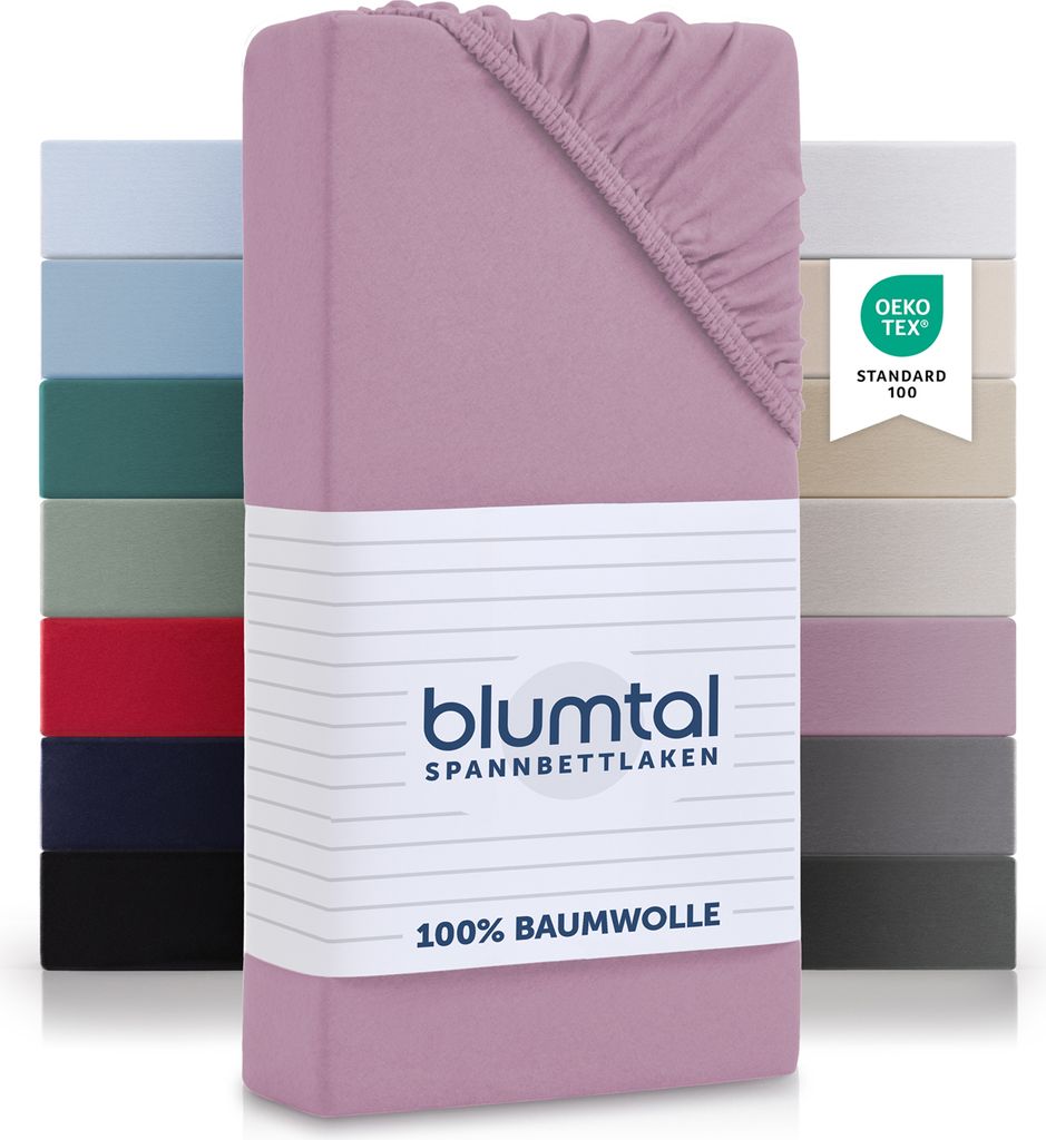 A stack of folded fitted sheets in various colors, with the main product in the foreground.