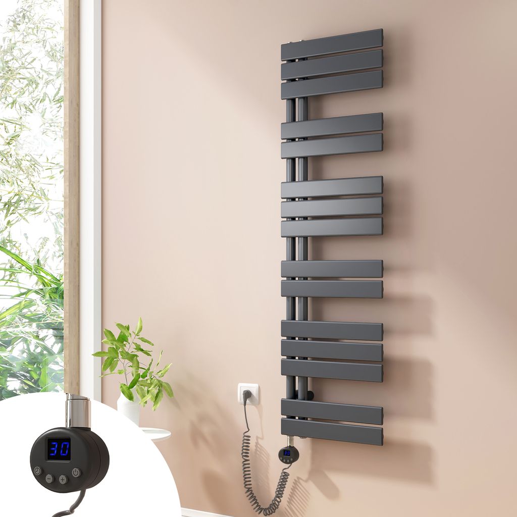 A modern anthracite electric towel radiator mounted on a light pink wall next to a window with greenery visible outside. A close-up inset shows the digital controller with a temperature display.