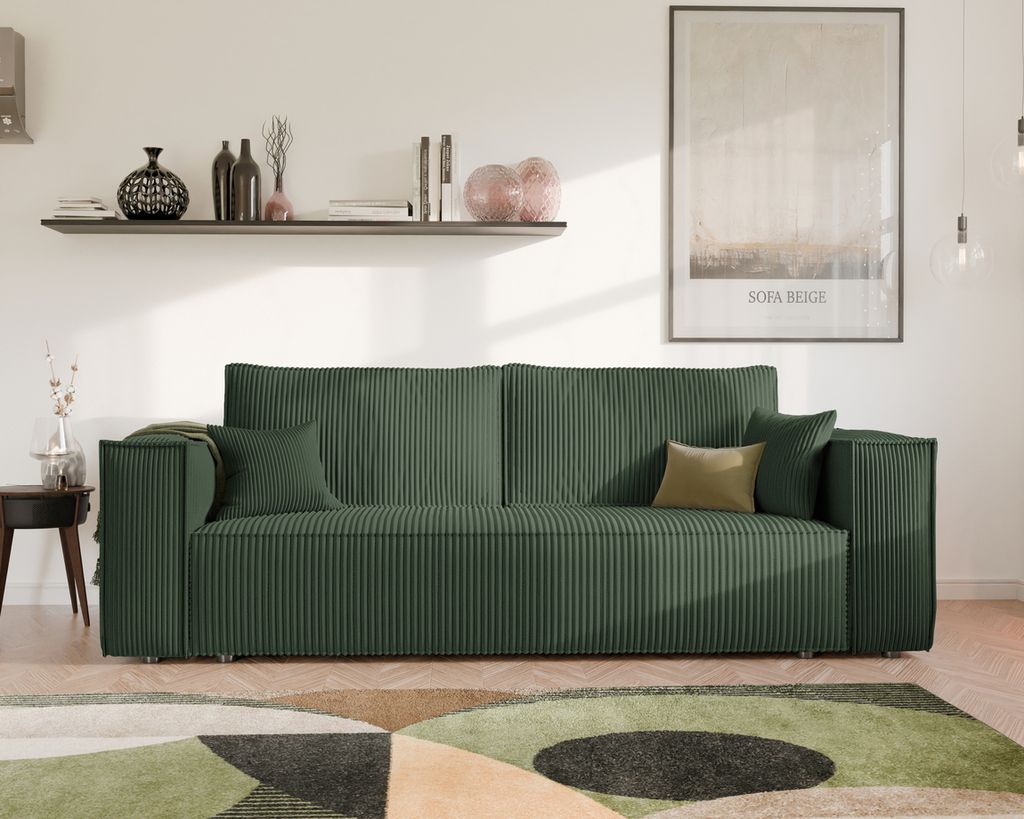 A green sofa is shown in a living room setting with a shelf and a framed picture on the wall.
