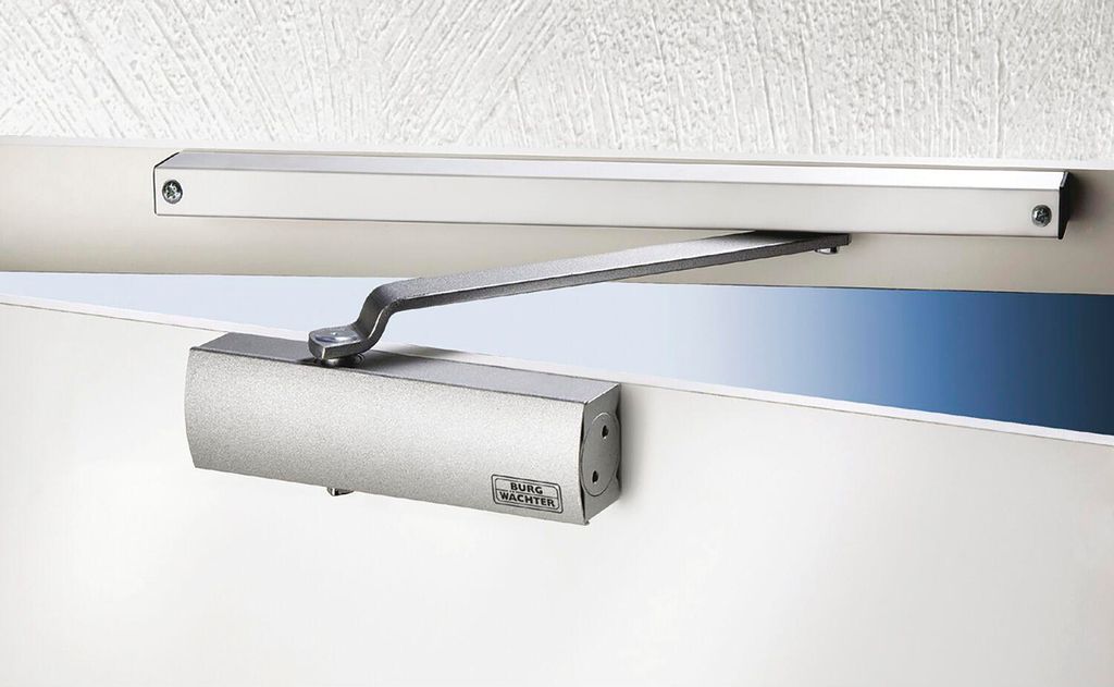 A close-up shot of a door closer mounted on a door and door frame.