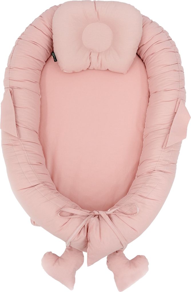 A pink baby nest with a small pillow attached.