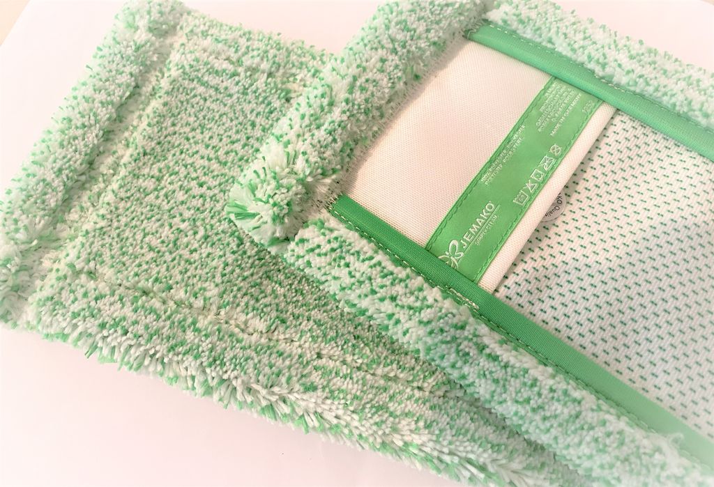 A close-up view of a green and white microfiber mop head, showing its texture and a label.