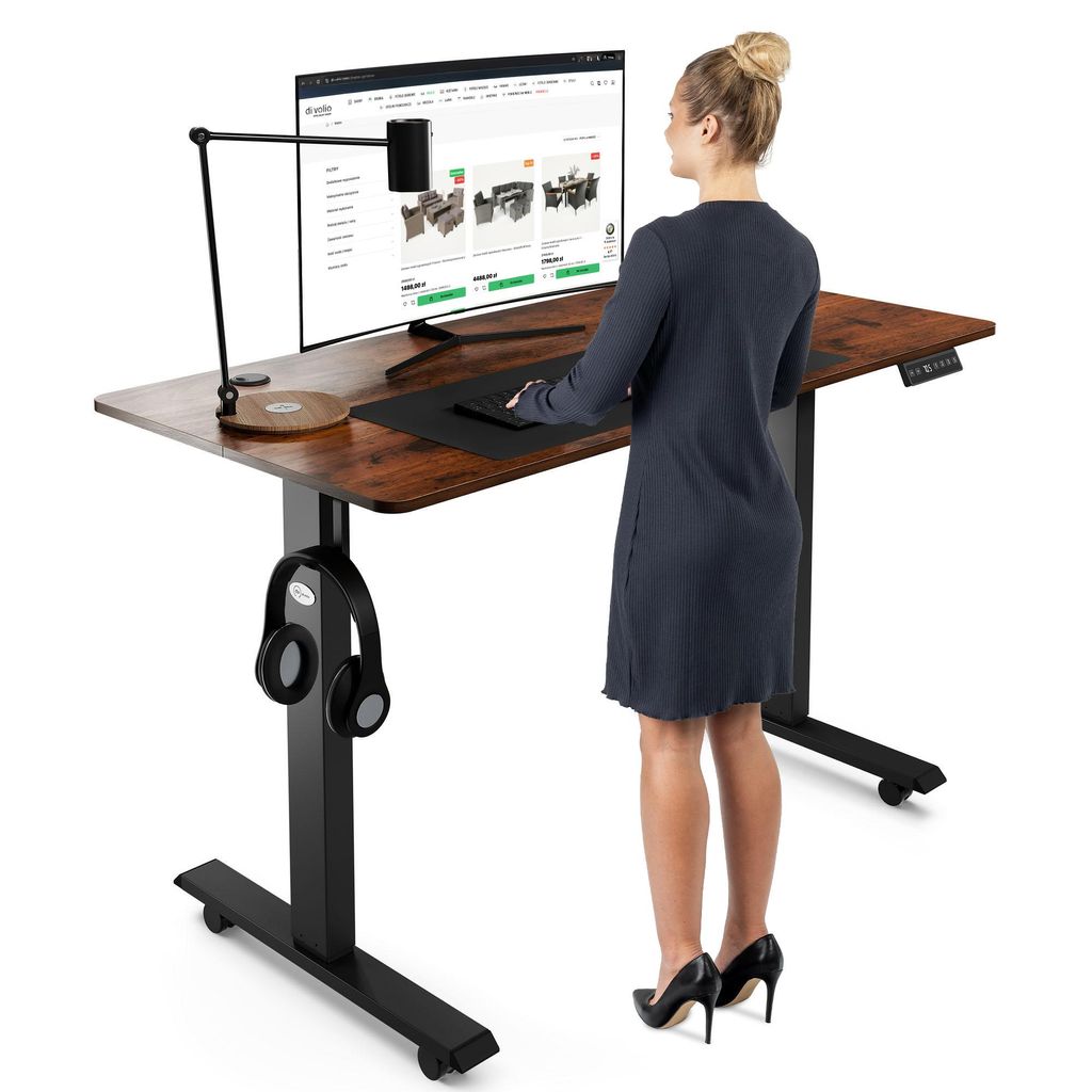 A woman is standing at a height-adjustable desk, using a computer.