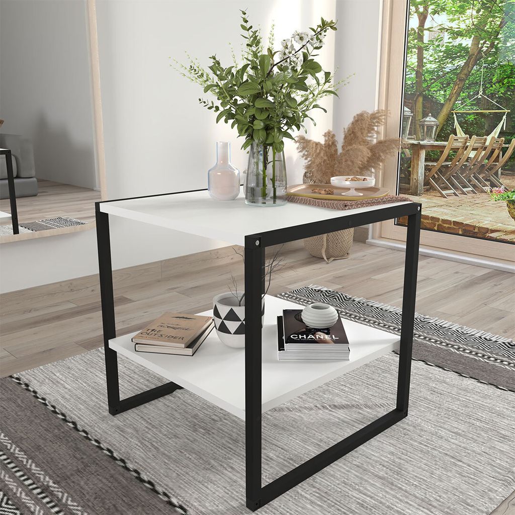 A modern coffee table with a minimalist design, placed in a living room setting with a view of a garden.