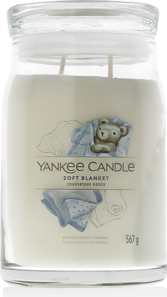 A Yankee Candle jar with a label showing a teddy bear wrapped in a blanket.