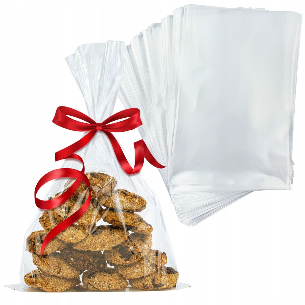 A clear plastic bag filled with cookies, tied with a red ribbon, and a stack of empty clear plastic bags in the background.