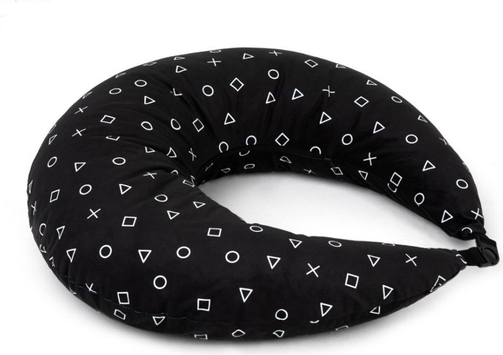 A black crescent-shaped pillow with a white geometric pattern of triangles, circles, squares, and crosses, set against a white background.