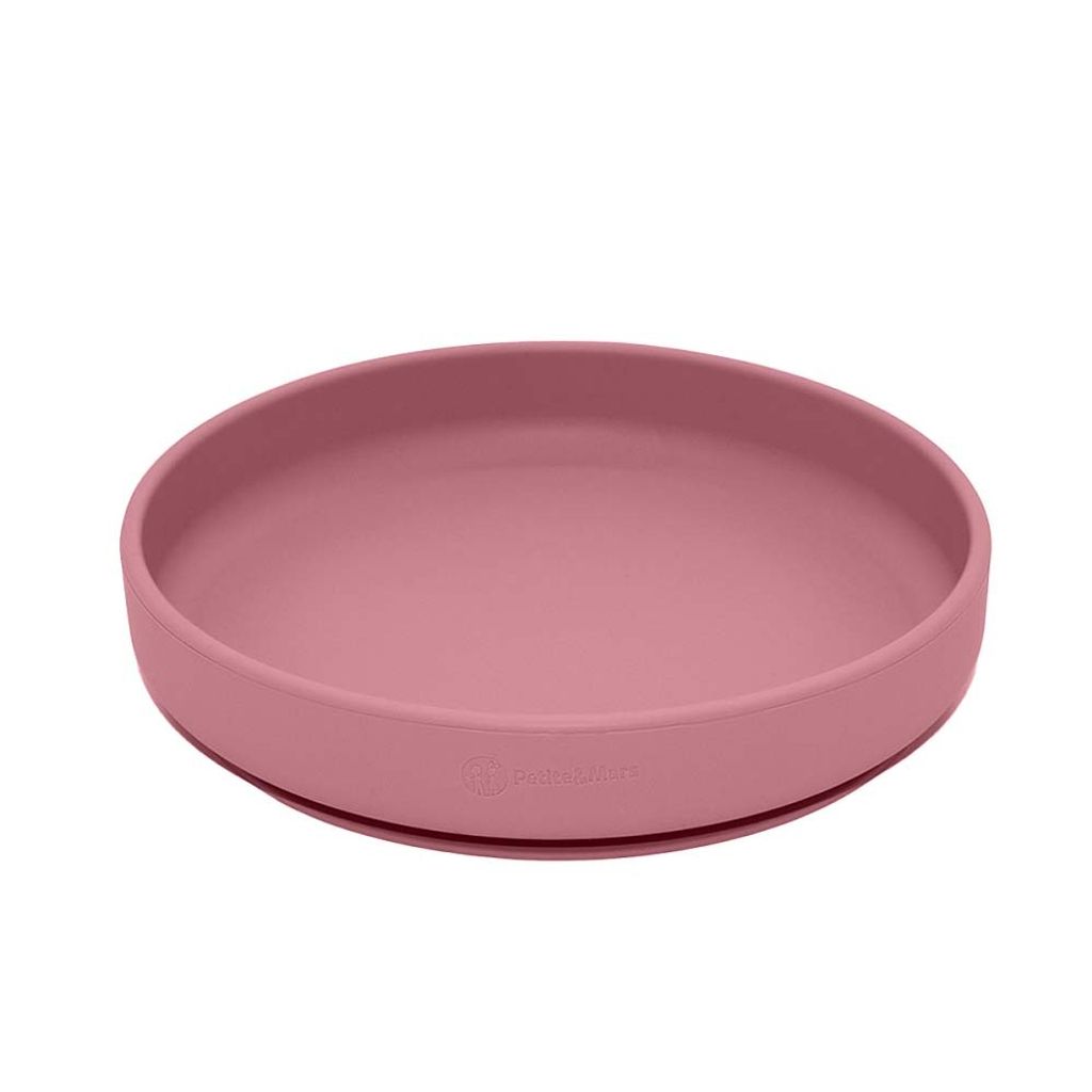 A pink silicone plate with a suction base, shown from a slightly elevated side angle against a white background.
