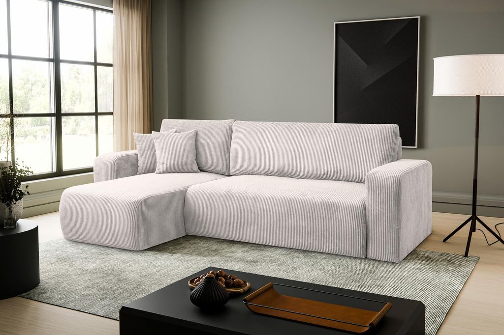A modern living room with a beige sectional sofa, a large window, and a black coffee table.