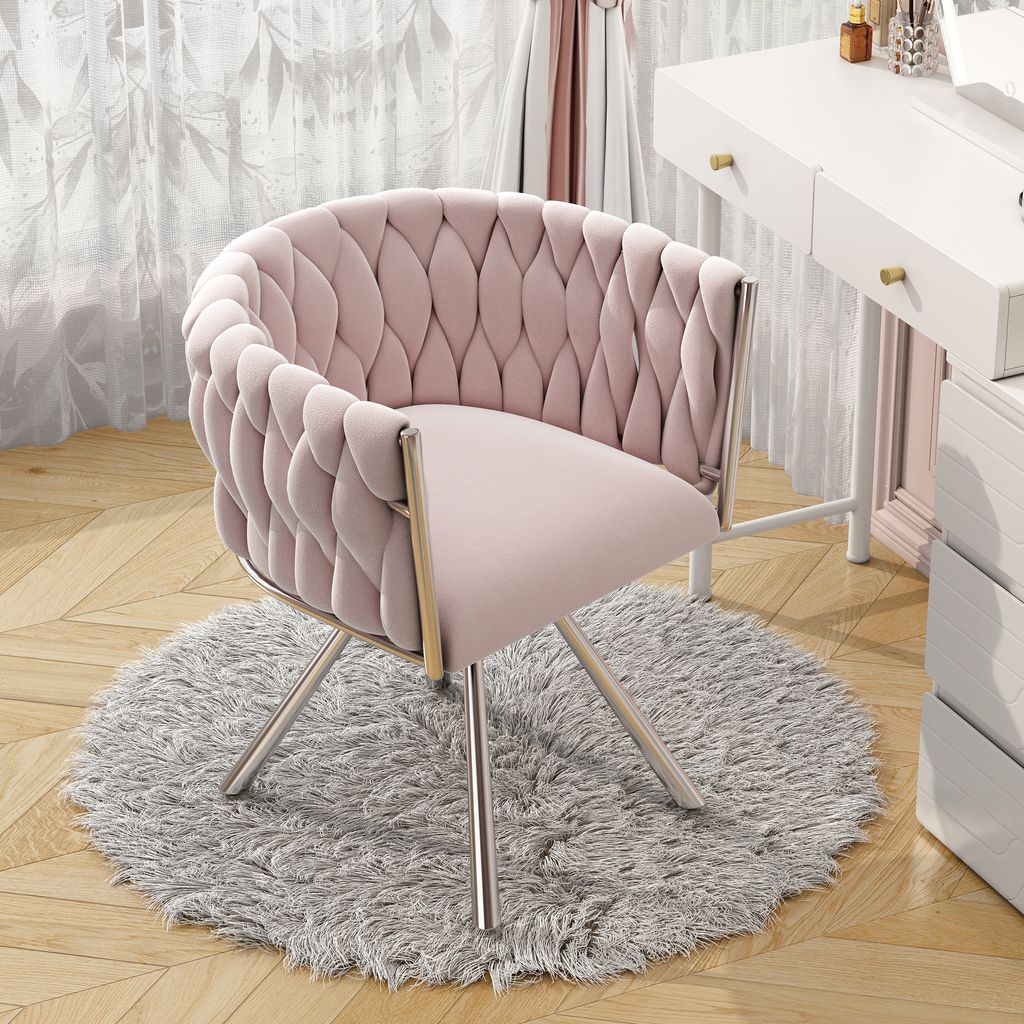 A pink velvet chair with silver legs sits on a fluffy gray rug next to a white vanity table.