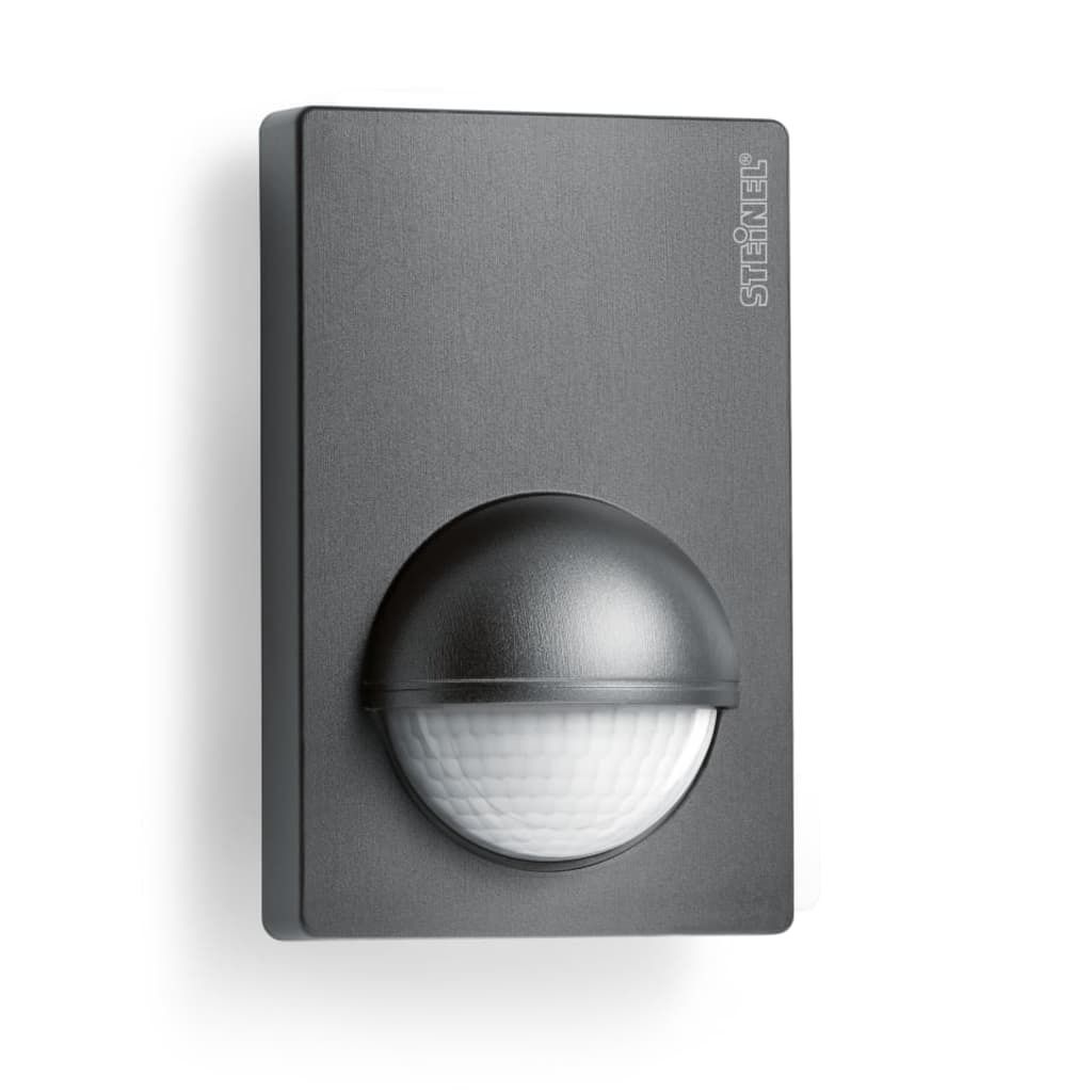 A dark grey motion sensor is mounted on a white wall.