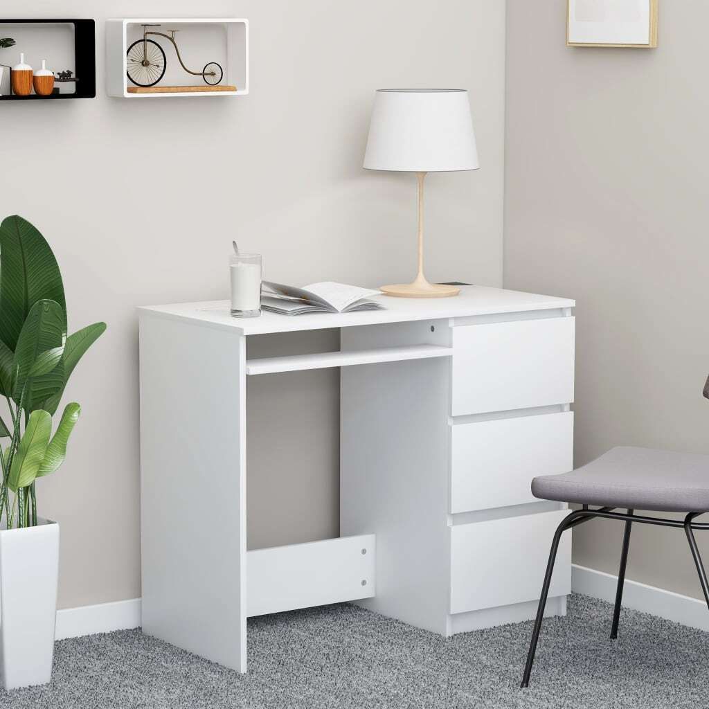 A white desk in a room setting, with a plant and shelves in the background.