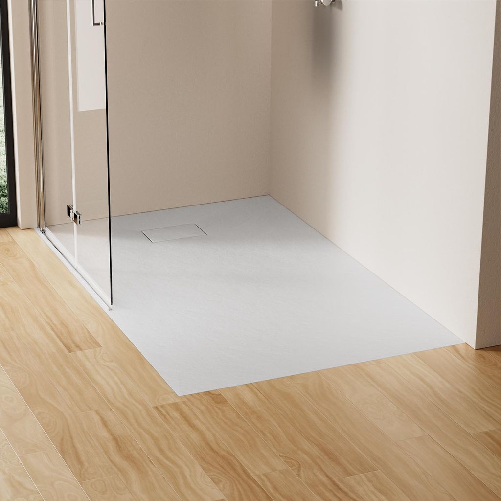A modern bathroom shower area with a white, flat shower tray and glass enclosure, adjacent to a wooden floor.