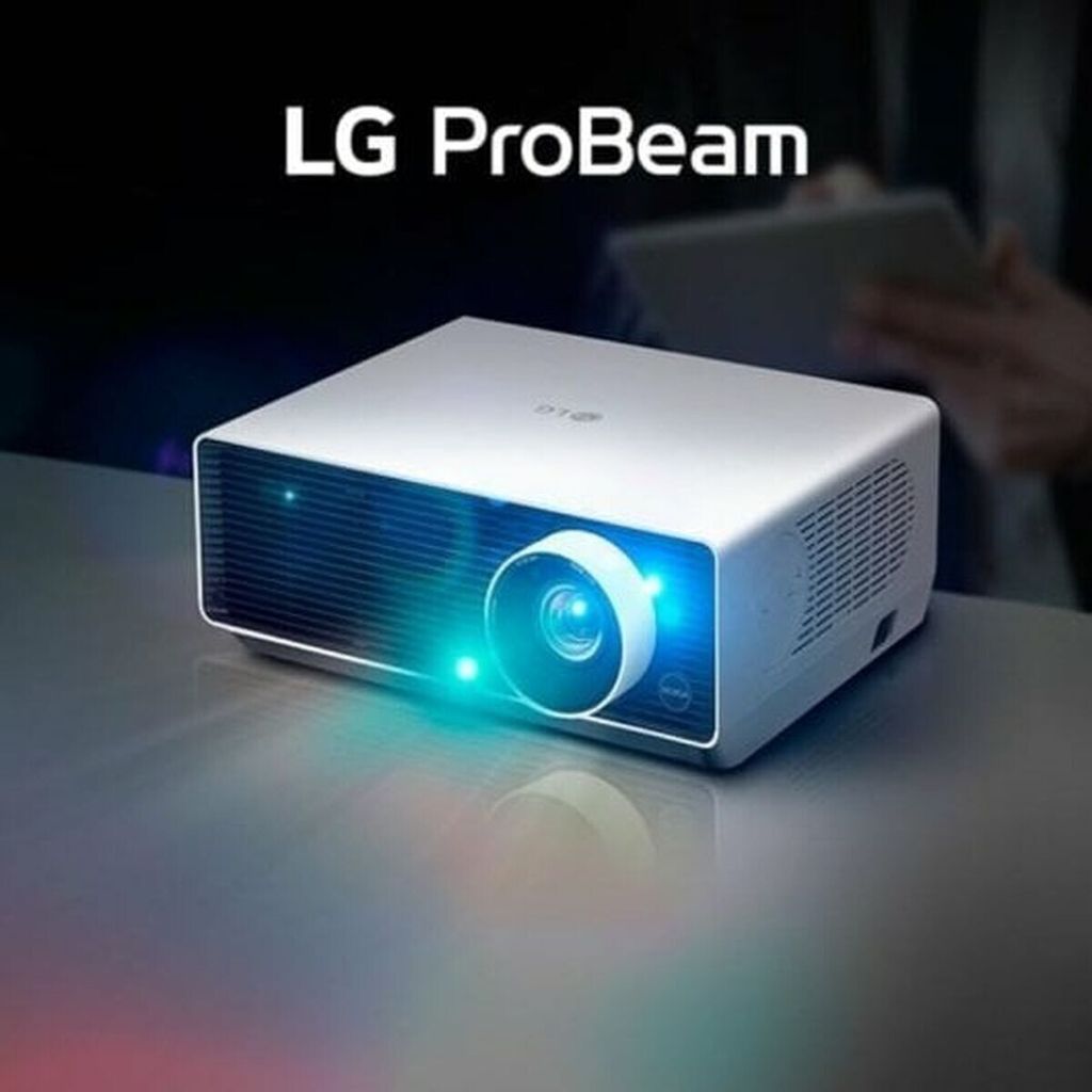 A white LG ProBeam projector is shown on a reflective surface, emitting a blue light. A person is visible in the background holding a tablet.