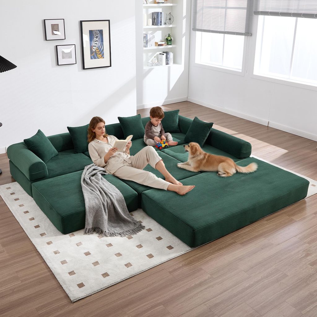 A family is relaxing on a modular green sofa in a living room.