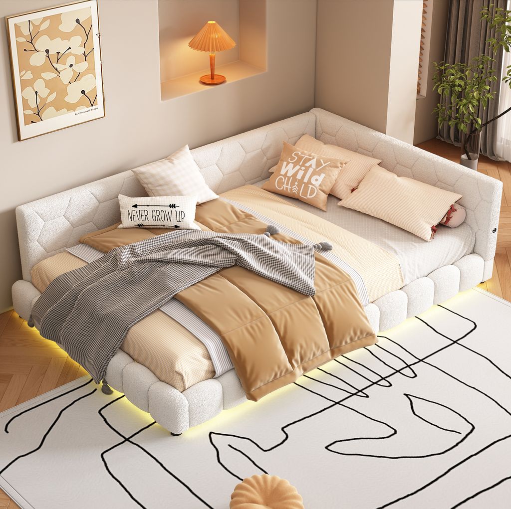 A corner bed with multiple pillows and blankets, illuminated by LED lights underneath.