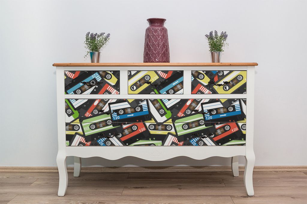 A dresser with drawers decorated with a cassette tape pattern, placed against a white wall.