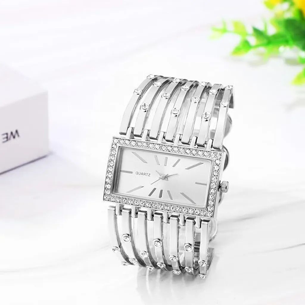 A silver women's watch with a rectangular face and a decorative bracelet is displayed on a white surface.