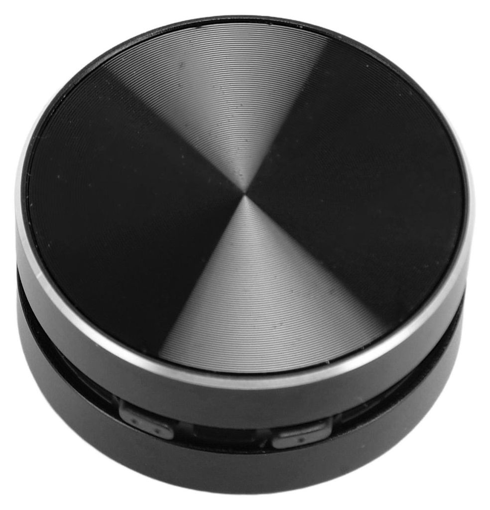 A close-up, studio shot of a small, round, black Bluetooth speaker with a metallic, brushed finish on its top surface.