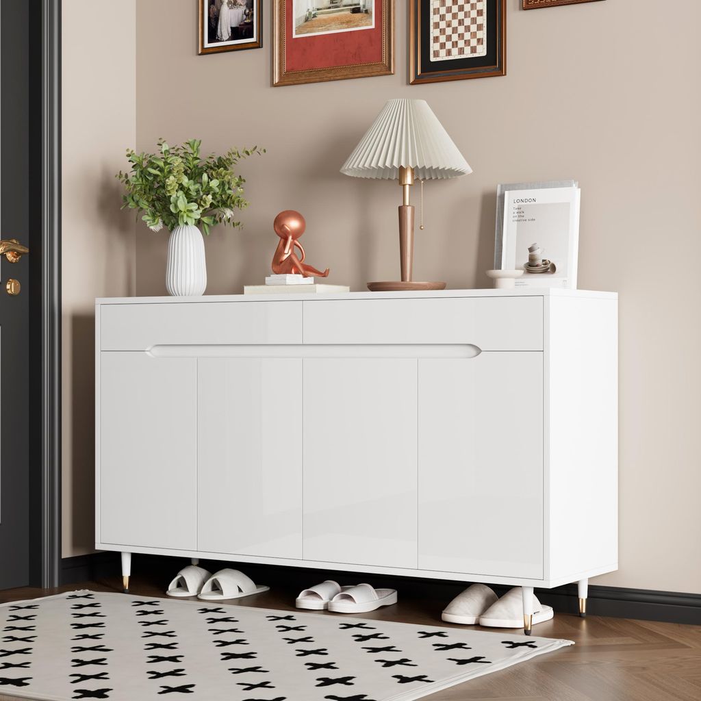 A white shoe cabinet with gold legs is shown in an entryway, with slippers placed underneath and a rug in front.
