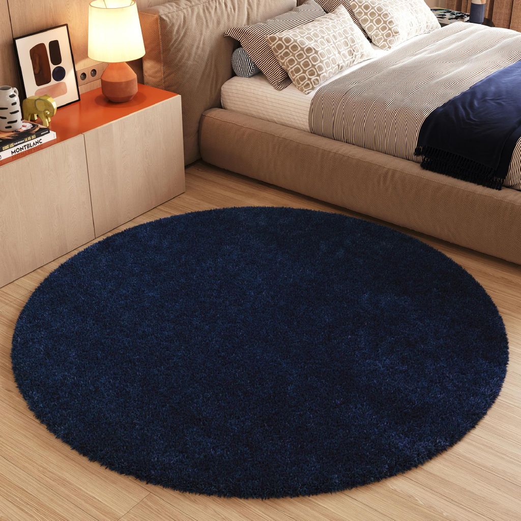 A bedroom scene with a bed, nightstand, and a round rug.
