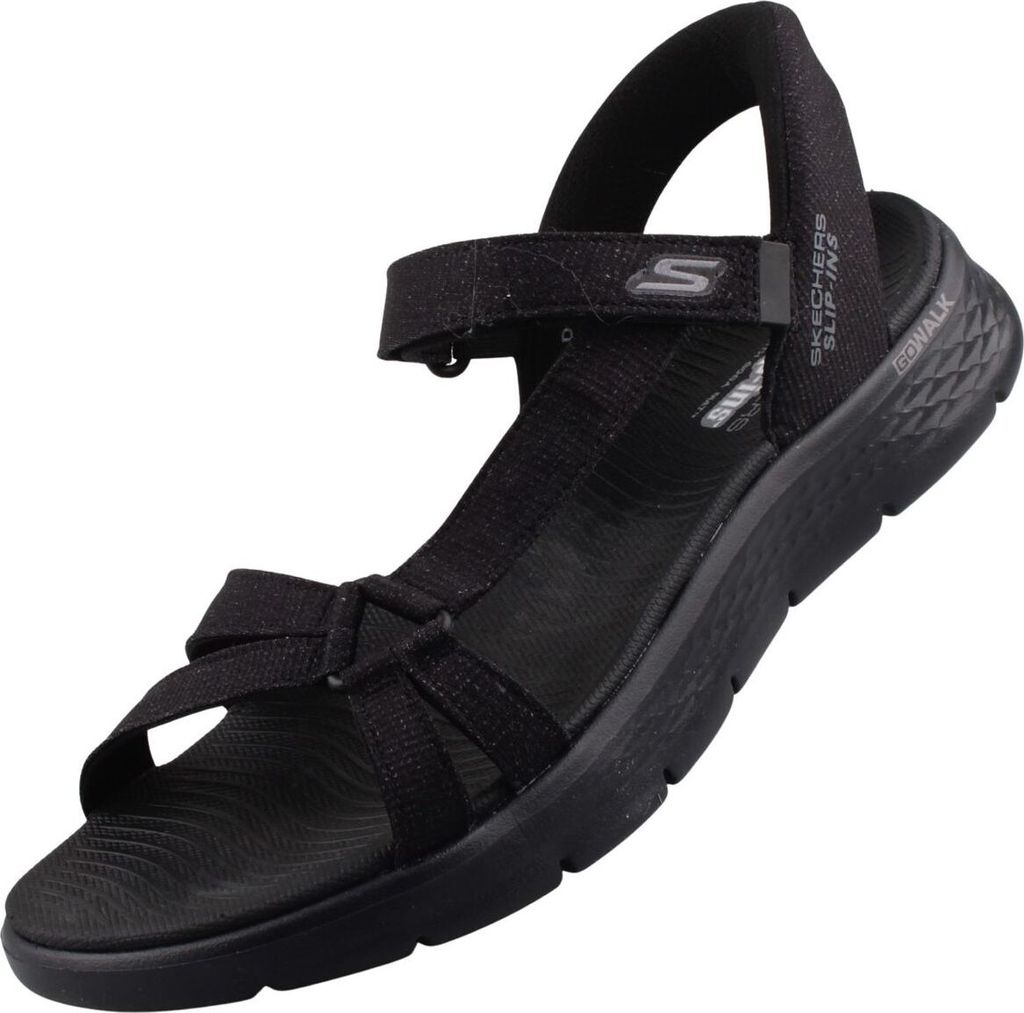 Auf dem Bild ist eine schwarze Sandale zu sehen die von der Seite abgebildet ist. Die Sandale hat ein schlichtes Design mit einem breiten Riemen über dem Fuß.