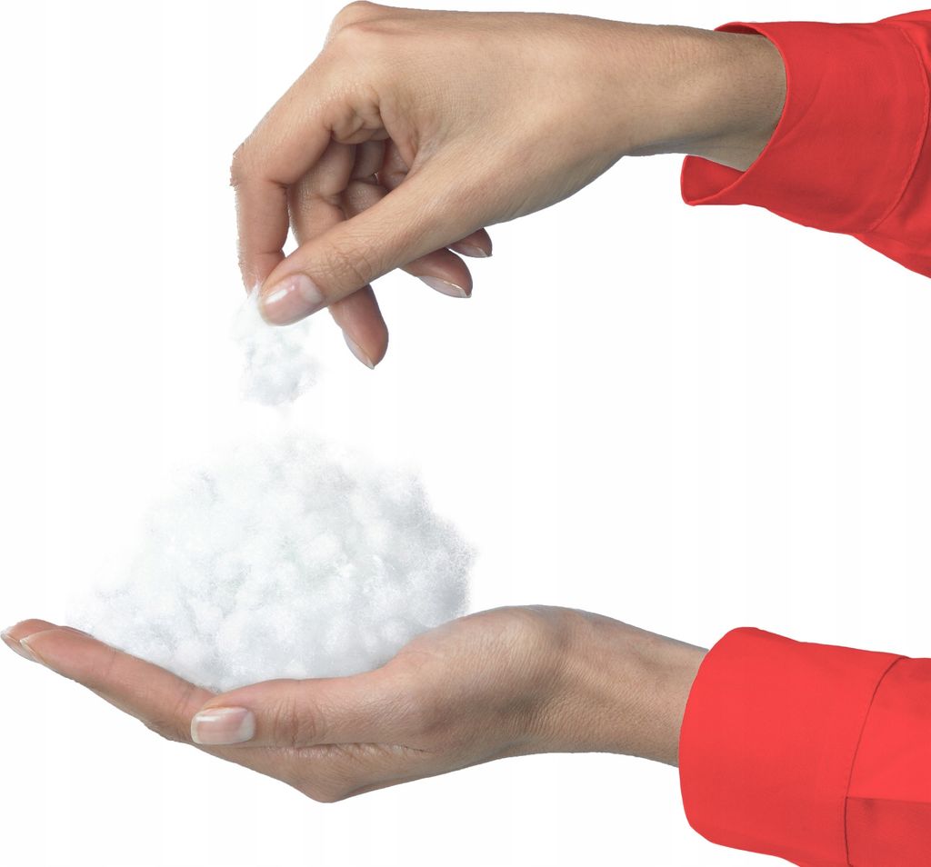 Hands holding and dropping white fluffy material.