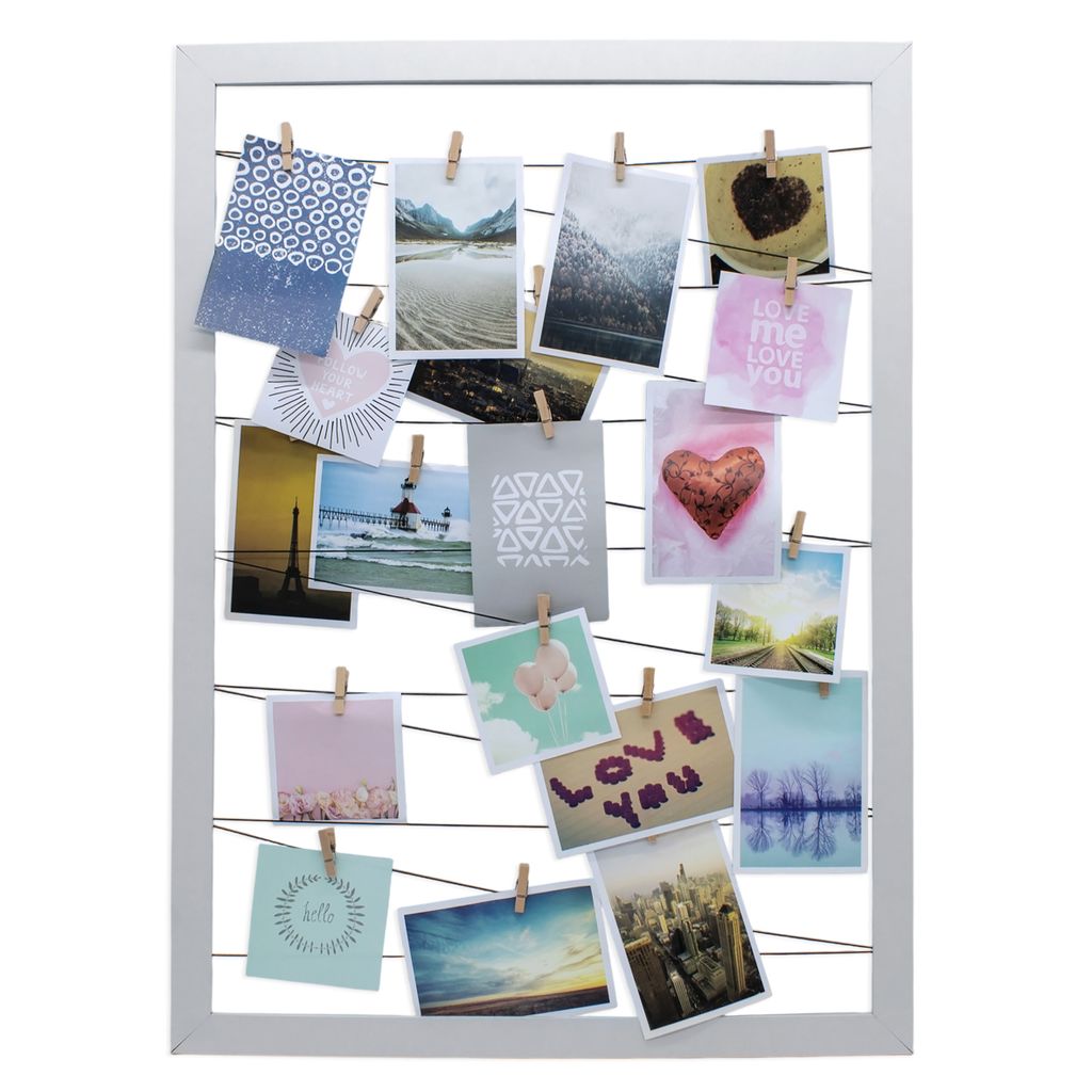 A white frame holding multiple photos attached with clips to thin wires.