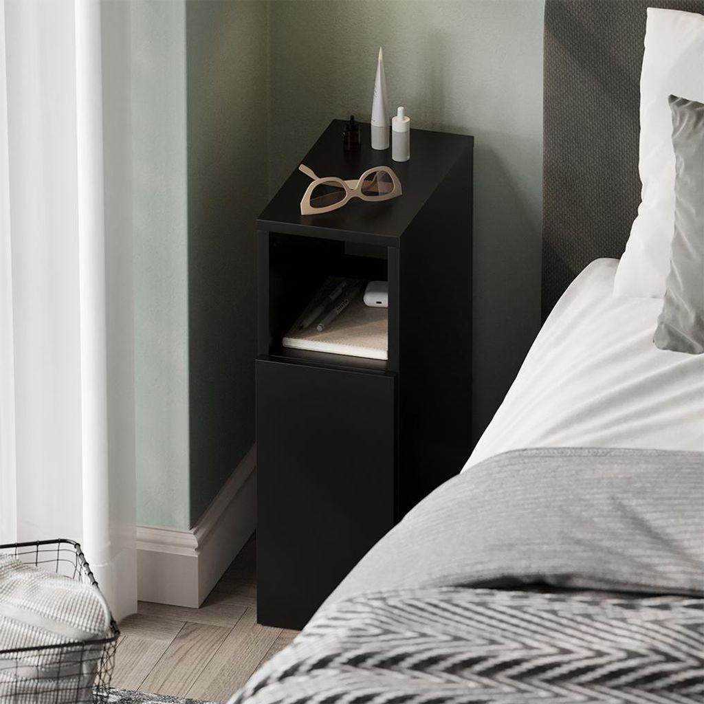 A black bedside table next to a bed, with a curtain and a basket in the foreground.