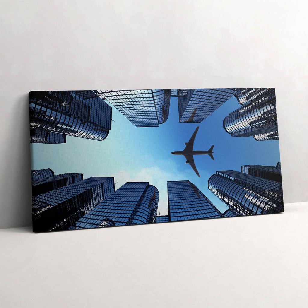 Flugzeug über Gebäude – Leinwandbild Wandbild – 100x50 cm – Leinwandbilder – Wandbilder – Schlafzimmer – Flur