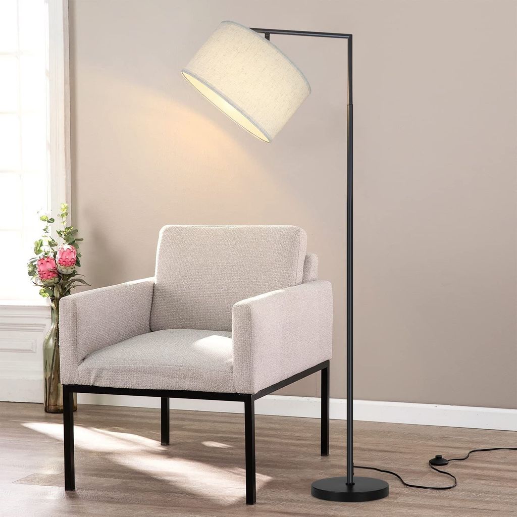 A modern floor lamp is positioned next to a beige armchair in a room.
