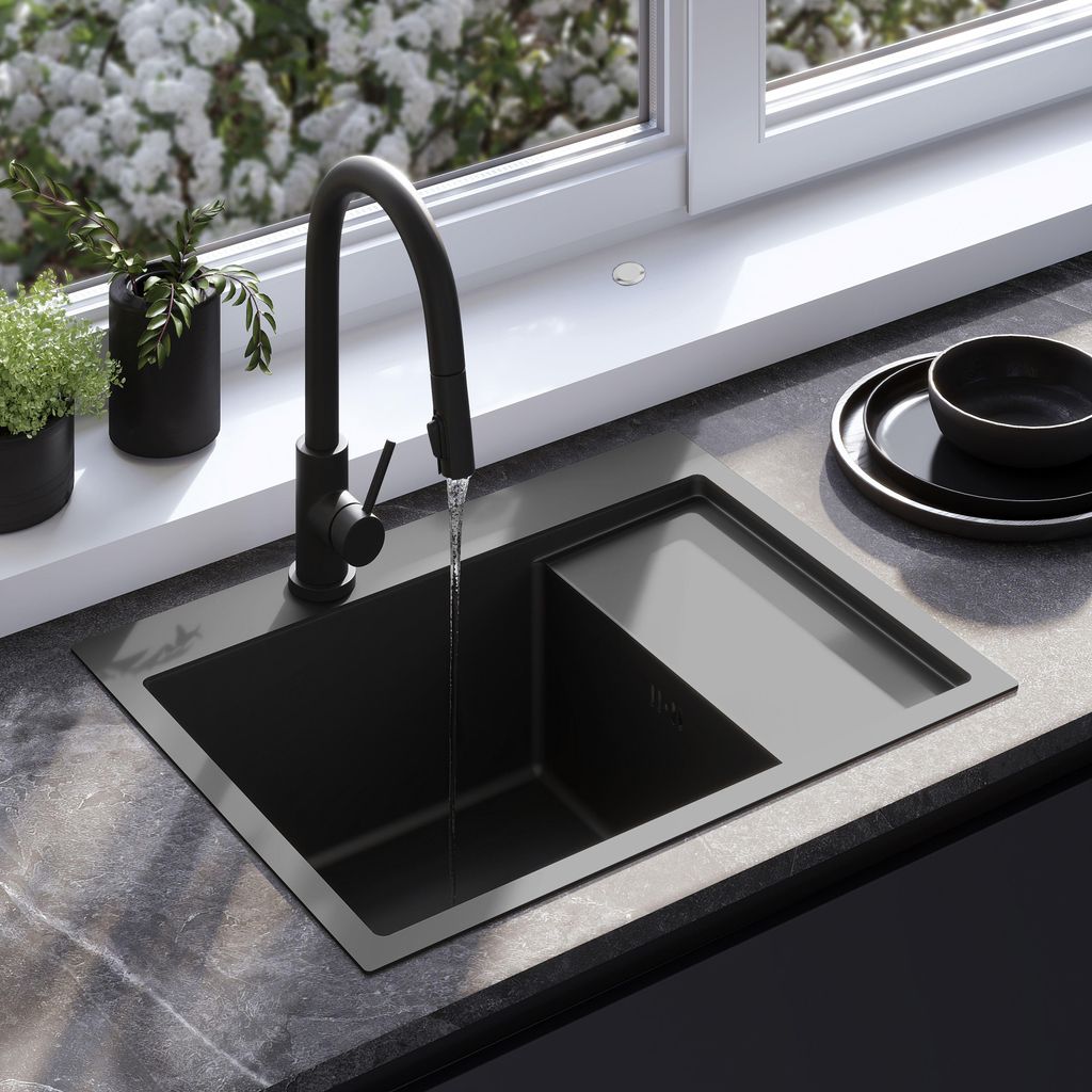A black sink with a faucet running water, set against a window with blooming flowers.