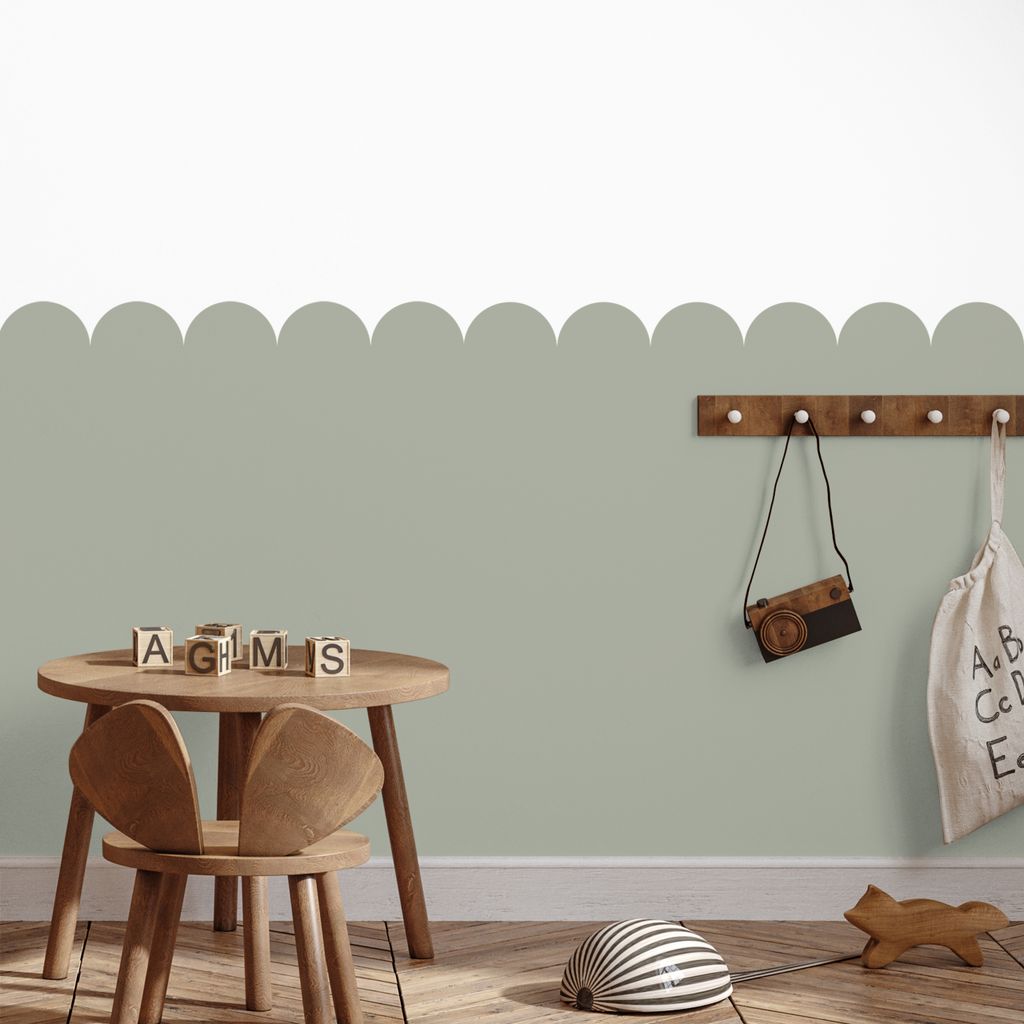 A child's room with a small wooden table and chair, wooden blocks, a toy camera, and a fabric bag hanging on a wall hook.
