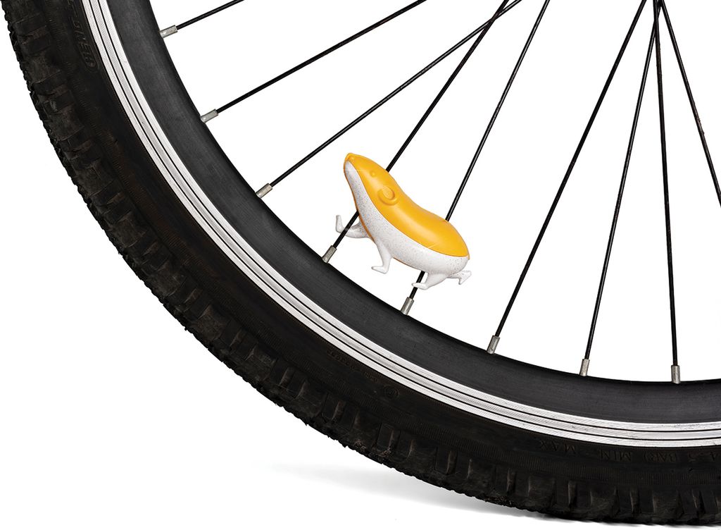 A close-up shot of a bicycle wheel with a small, yellow and white hamster-shaped accessory attached to the spokes.