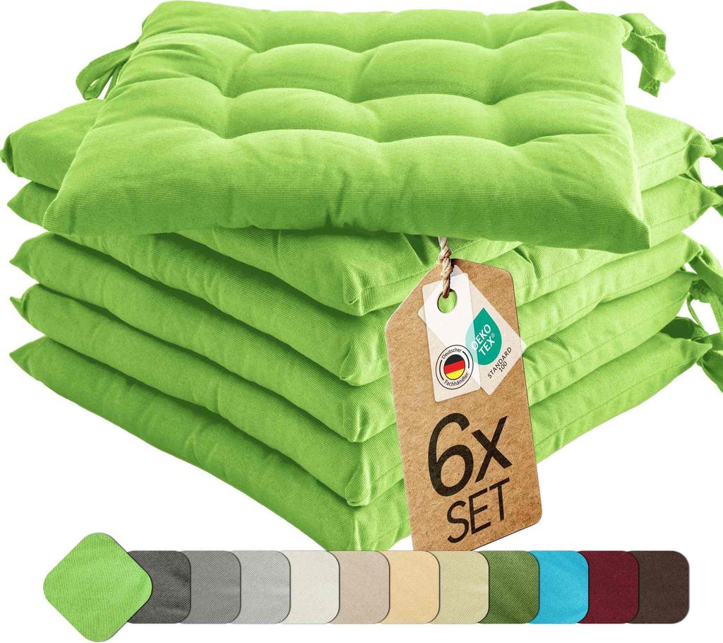 A stack of six green seat cushions with a tag attached.