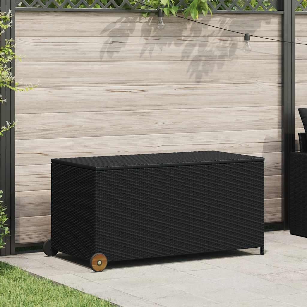 A black poly rattan storage box with wheels is placed on a patio in front of a wooden fence.