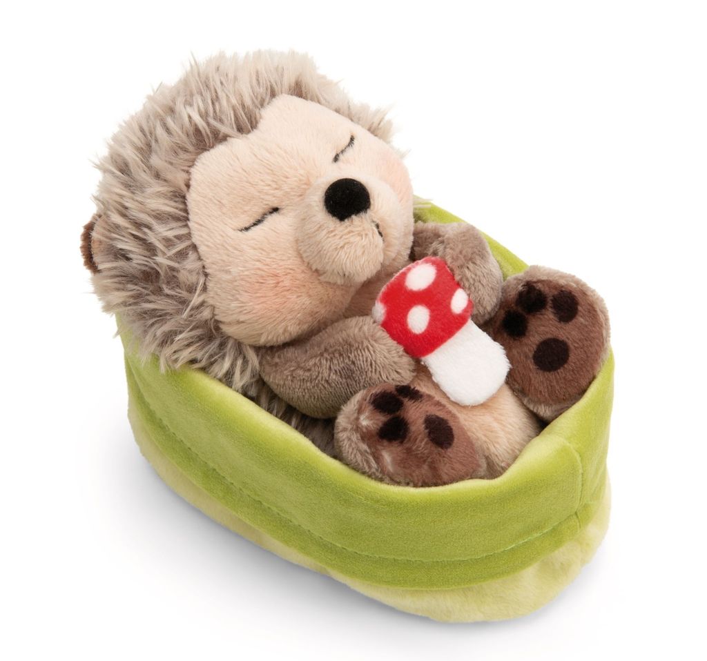 A plush toy hedgehog sleeping in a green basket with a mushroom.