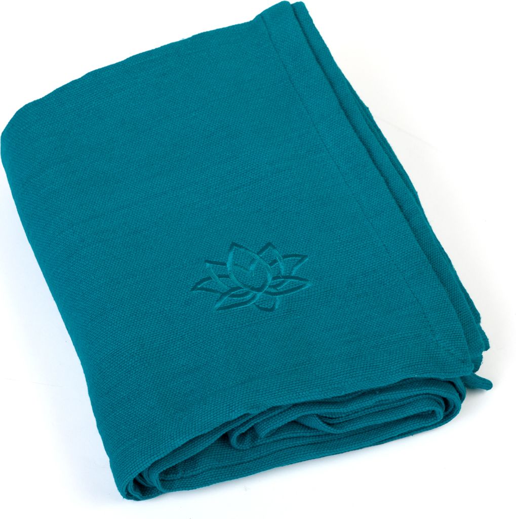 A folded teal yoga blanket with a lotus flower embossed on it, shown on a white background.