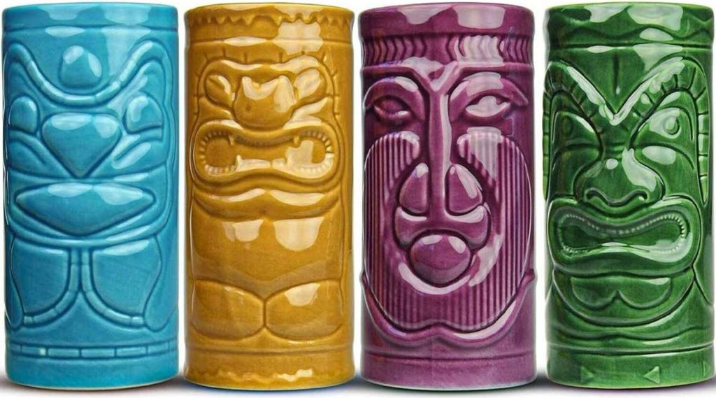 Four tiki mugs in different colors lined up against a white background.