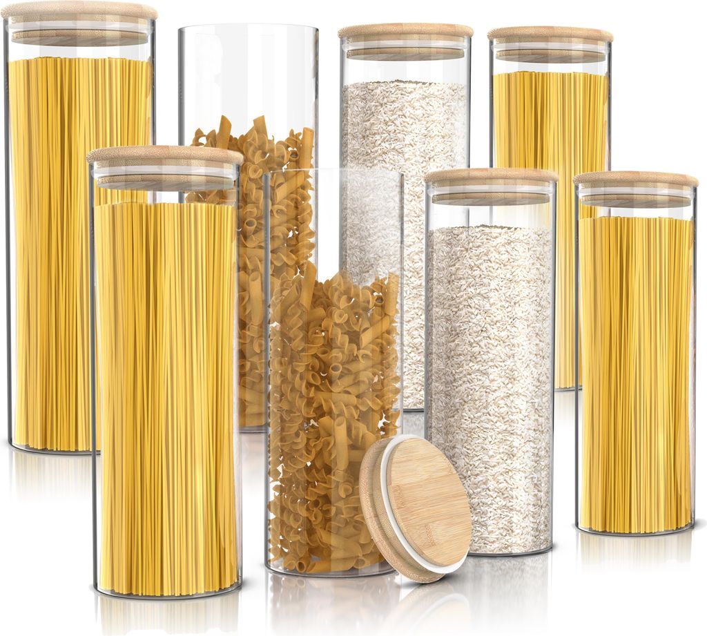 A collection of glass storage jars filled with pasta and grains, with bamboo lids.