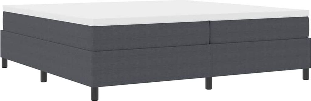 A dark gray boxspring bed with a white mattress on top, shown from a side-angle against a white background.
