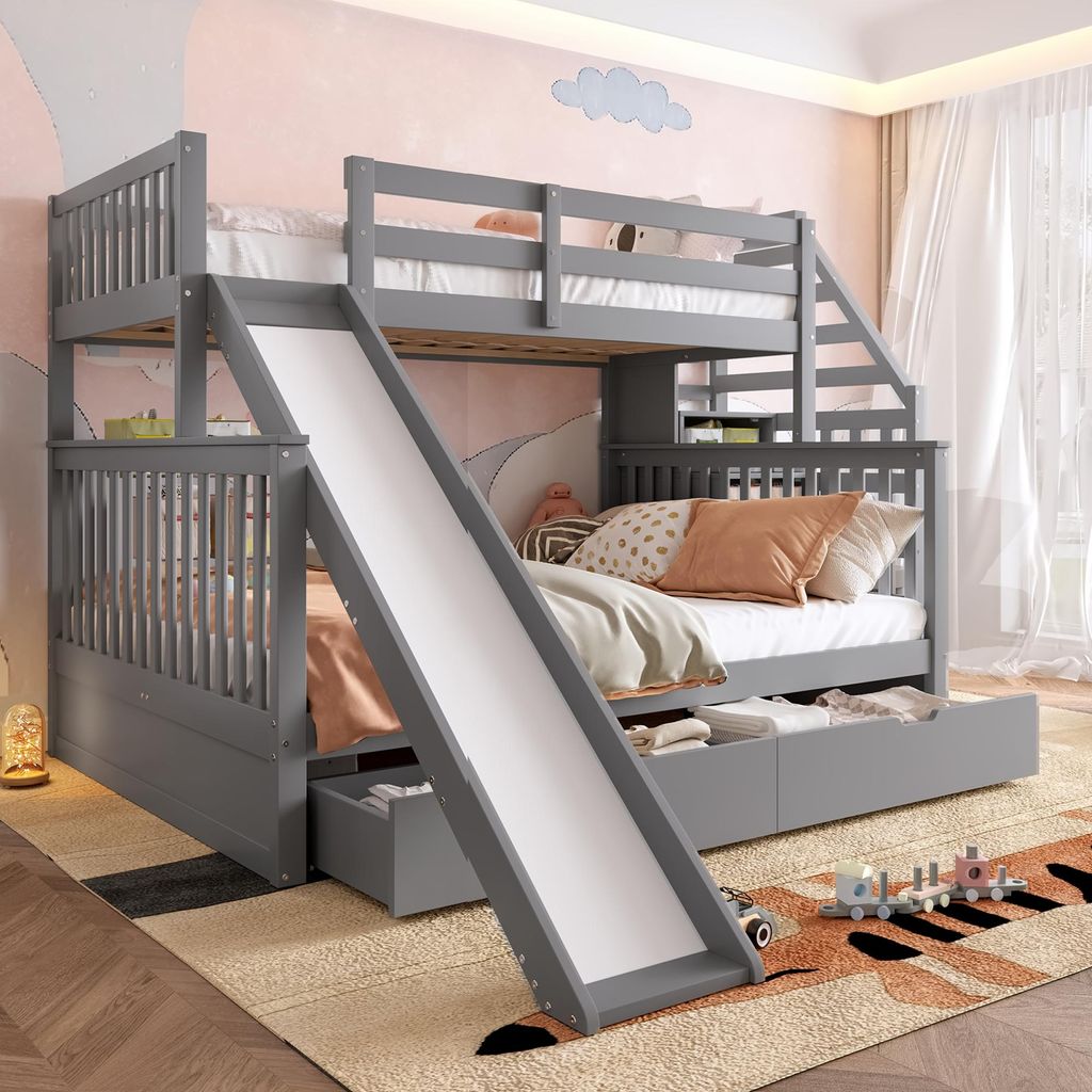 A children's bunk bed with a slide and storage drawers, set in a bedroom with a whimsical mural on the wall.
